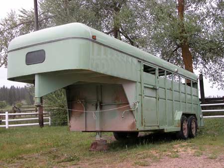 Photo of a green horse trailer.